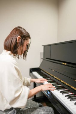 30 'lu yaşlarında bir Japon kadın evde piyano çalıyor..