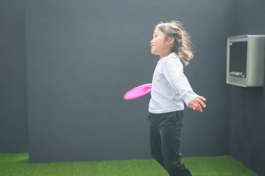 Japon bir ebeveyn ve çocuk, 20 'li yaşlarda bir adam ve 6 yaşında bir kız, evlerinin duvarlı bahçesinde bir öğleden sonra frizbi oynuyorlar..
