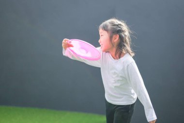 Japon bir ebeveyn ve çocuk, 20 'li yaşlarda bir adam ve 6 yaşında bir kız, evlerinin duvarlı bahçesinde bir öğleden sonra frizbi oynuyorlar..