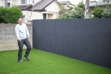Japon bir ebeveyn ve çocuk, 20 'li yaşlarda bir adam ve 6 yaşında bir kız, evlerinin bahçesinde birbirlerine yeşil plastik toplar atarak oynuyorlar..