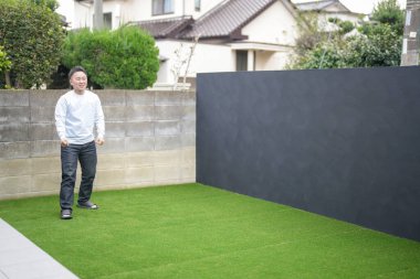 Japon bir ebeveyn ve çocuk, 20 'li yaşlarda bir adam ve 6 yaşında bir kız, evlerinin bahçesinde birbirlerine yeşil plastik toplar atarak oynuyorlar..