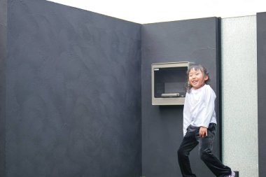 Japon bir ebeveyn ve çocuk, 20 'li yaşlarda bir adam ve 6 yaşında bir kız, evlerinin bahçesinde birbirlerine yeşil plastik toplar atarak oynuyorlar..