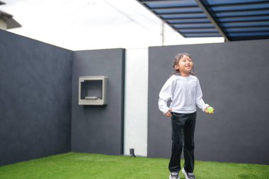 Japon bir ebeveyn ve çocuk, 20 'li yaşlarda bir adam ve 6 yaşında bir kız, evlerinin bahçesinde birbirlerine yeşil plastik toplar atarak oynuyorlar..