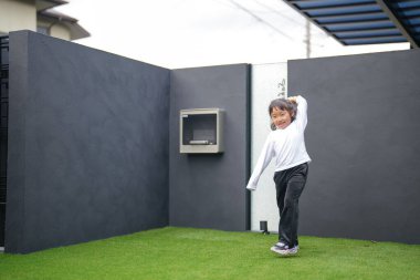 Japon bir ebeveyn ve çocuk, 20 'li yaşlarda bir adam ve 6 yaşında bir kız, evlerinin bahçesinde birbirlerine yeşil plastik toplar atarak oynuyorlar..