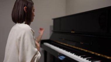 Genç Asyalı kadın oturma odasında piyano çalıyor..