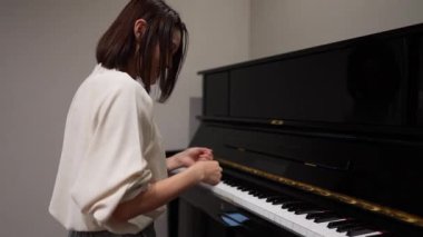 Genç Asyalı kadın oturma odasında piyano çalıyor..