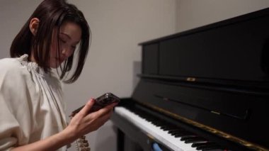 Genç Asyalı kadın oturma odasında piyano çalıyor..