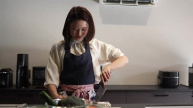 Asyalı kadın mutfakta yemek yapıyor.