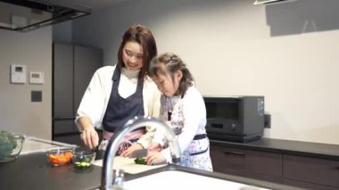 Asyalı anne ve kız mutfakta yemek yapıyorlar.