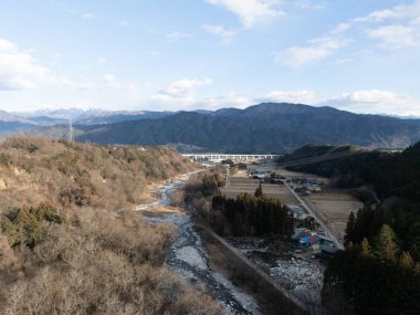 Pirinç tarlaları ve karla kaplı dağ da dahil olmak üzere özel evler de dahil olmak üzere kırsal alanın havadan çekilmiş fotoğrafı. Senjogatake ve Mt. Kiso-Komagatake, Komagane Şehri, Nagano Bölgesi, Japonya, kışın. 