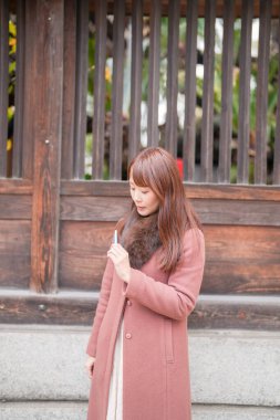 Japonya 'daki tarihi binaların yanında. 30 'lu yaşlarda uzun saçlı bir Japon kadın elektronik sigara içerek şehre bakıyor..