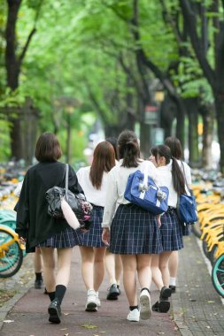 Yazın başlarında, Şangay 'ın Pudong bölgesinde, yaz üniformalı yedi Japon liseli kız okula giderken ağaçlık bir cadde boyunca yürüyorlar, gülümseyerek, arkadan görülüyorlar..