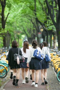 Yazın başlarında, Şangay 'ın Pudong bölgesinde, yaz üniformalı yedi Japon liseli kız okula giderken ağaçlık bir cadde boyunca yürüyorlar, gülümseyerek, arkadan görülüyorlar..