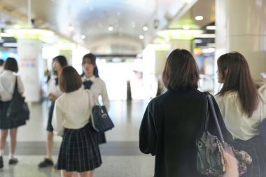 Şangay 'da, üniformalı bir grup Japon liseli kız, bir yeraltı geçidinde yürürler, yumuşak bir şekilde sohbet ederler ve şehrin sabah trafiğine ayak uydururken birbirlerine yakın dururlar..