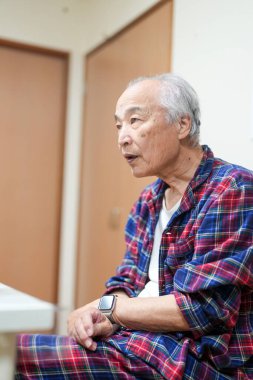 70 'li yaşlarının sonlarında kareli pijama giyen bir Japon, Japonya' da hafif aydınlatılmış bir apartman dairesinde tek başına viski içmekten hoşlanıyor. Sıcak atmosfer huzurlu bir bahar akşamının sessiz bir yansıması olduğunu gösteriyor..