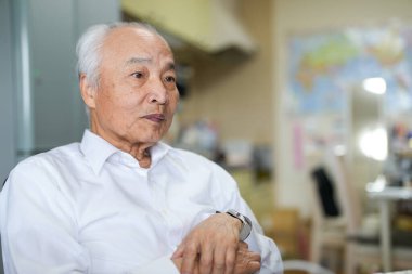 Japonya 'da sessiz bir dairede, 70' li yaşlarının sonunda beyaz tişörtlü bir adam masasında oturmuş bilgisayarında interneti karıştırıyor ve günlük barışçıl hayatını yansıtıyor.