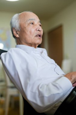 Japonya 'da sessiz bir dairede, 70' li yaşlarının sonunda beyaz tişörtlü bir adam masasında oturmuş bilgisayarında interneti karıştırıyor ve günlük barışçıl hayatını yansıtıyor.