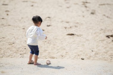Mart ayı başlarında, beyaz giyinmiş 3 yaşındaki Japon bir kız kuma basmadan önce ayakkabılarını dikkatlice çıkarıyor. Yumuşak bir bahar anı sahildeki farkındalığı ve masumiyeti yakalıyor..