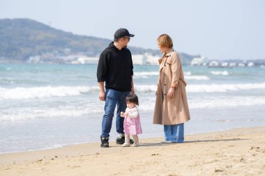 Mart ayı başlarında, 30 'lu yaşlardaki ebeveynleri onu yakından izlerken 1 yaşındaki bir Japon kız merakla plajı keşfediyor. Bahar mevsiminde, deniz kıyısında bağ ile dolu sıcak bir aile anı..