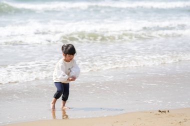 Mart ayı başlarında, beyaz kıyafetli 3 yaşındaki bir Japon kız Japon Denizi manzaralı kumlu bir plajda tek başına koşup oynuyor. Masumiyet ve özgürlükle dolu neşeli bir bahar anı.