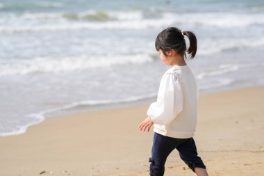 Mart ayı başlarında, beyaz kıyafetli 3 yaşındaki bir Japon kız Japon Denizi manzaralı kumlu bir plajda tek başına koşup oynuyor. Masumiyet ve özgürlükle dolu neşeli bir bahar anı.