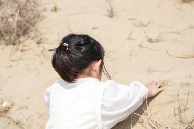Mart ayı başlarında, beyaz kıyafetli 3 yaşındaki bir Japon kız Japon Denizi manzaralı kumlu bir plajda tek başına koşup oynuyor. Masumiyet ve özgürlükle dolu neşeli bir bahar anı.