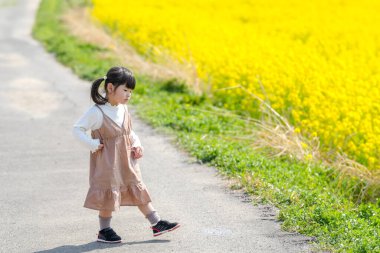 Huzurlu bir kırsal alanda, ikiz at kuyruklu 3 yaşındaki Japon bir kız Mart ayı başında çiçek açan kolza çiçeği tarlasında yürür ve baharın cazibesini somutlaştırır..