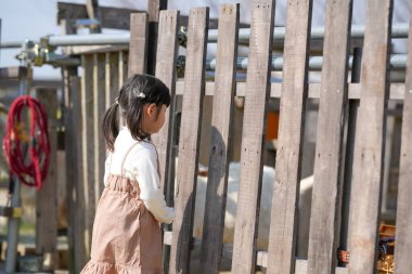 İkiz kuyruklu neşeli bir Japon kızı, Mart ayında güneşli bir bahar öğleden sonrasını sakin bir kırsal alanda yumuşak, sıcak güneş ışığıyla yıkanmış bir keçiyi yeşil otla besleyerek geçiriyor..