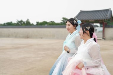 Haziran 'da Seul' de, 30 'lu yaşlarda iki Koreli kadın Gyeongbokgung Sarayı' nda yürür ve konuşurlar, büyüleyici pembe ve gökyüzü mavisi Hanbok giyerek, gülüşleri temiz bir yaz gökyüzü altında zengin bir tarihi yansıtır..