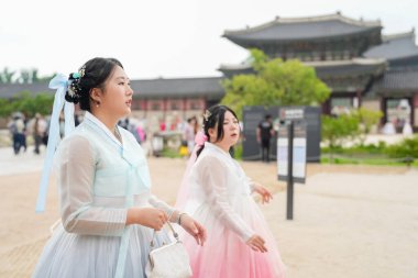 Haziran 'da Seul' de, 30 'lu yaşlarda iki Koreli kadın Gyeongbokgung Sarayı' nda yürür ve konuşurlar, büyüleyici pembe ve gökyüzü mavisi Hanbok giyerek, gülüşleri temiz bir yaz gökyüzü altında zengin bir tarihi yansıtır..