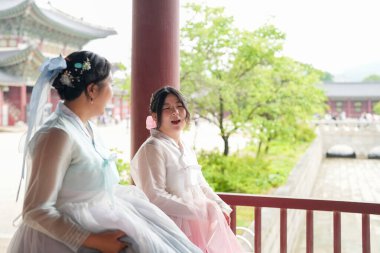 Haziran 'da Seul' de, 30 'lu yaşlarda iki Koreli kadın Gyeongbokgung Sarayı' nın büyük taş sütunlarının altında yürür, şirin pembe ve gökyüzü mavisi Hanbok giyip tarihi mekanı aydınlatmaya çalışırken konuşurlar..