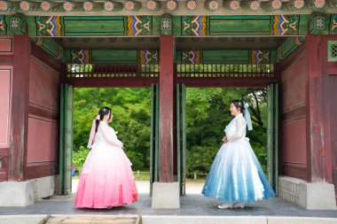 Haziran 'da Seul' de, yirmili yaşlarda iki Koreli kadın açık bir yaz gökyüzü altında büyüleyici pembe ve gökyüzü mavisi Hanbok giyen Gyeongbokgung Sarayı 'nın görkemli antik kapısının önünde yan yana dururlar..