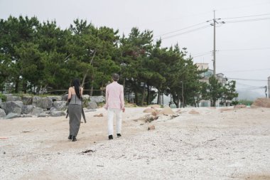 Haziran 2025 'te, 50' li yaşların sonlarında bir Koreli erkek ve kadın, sakin okyanus esintisinin, sessiz anların ve Incheon Metropolitan City 'de birbirlerinin arkadaşlığının tadını çıkararak, huzurlu deniz kıyısında yürürler..