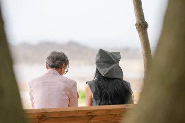 Haziran 2025 'te, 50' li yaşlarının sonlarında bir Koreli erkek ve kadın deniz kenarındaki bir bankta oturup esinti, okyanus manzarası ve Incheon Metropolitan City 'nin sakin ortamının tadını çıkarırken sohbet ediyor ve gülümsüyor..