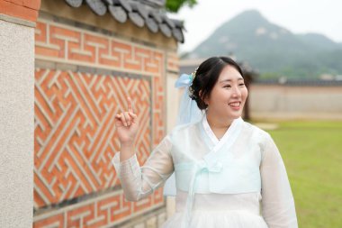 Haziran 2025 'te Seul' de, 20 'li yaşlarda iki Koreli kadın pembe ve gökyüzü mavisi Hanbok giyerek Gyeongbokgung Sarayı' nın geleneksel tuğla kapısının önünde duruyorlardı..