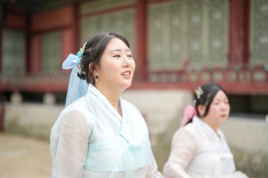 Seul, Haziran 2025: 20 'li yaşlarda iki Koreli kadın pembe ve gökyüzü mavisi Hanbok' la Gyeongbokgung Sarayı 'nda geziniyor. Yaz ışığında yıkanırlar, tarihi güzellikler arasında kahkahaları paylaşırlar..