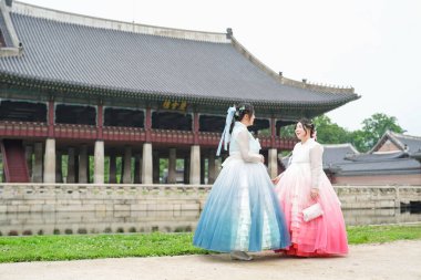 Haziran 'da Seul' de, yirmili yaşlarında iki Koreli kadın Gyeongbokgung Sarayı 'nın sakin su setinde sevimli pembe ve gökyüzü mavisi bir Hanbok giyip açık bir yaz gökyüzünün altında gülümsüyor..