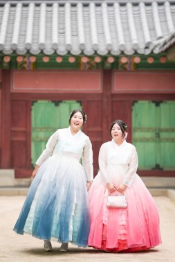 Yirmili yaşlarda iki Koreli kadın, Gyeongbokgung Sarayı 'nda, yumuşak, berrak bir yaz gökyüzünün altında, sevimli pembe ve gökyüzü mavisi Hanbok' a zarif bir şekilde dönüp bakıyorlar. Seul, Haziran.