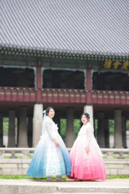 Haziran 'da Seul' de, yirmili yaşlardaki iki Koreli kadın Gyeongbokgung Sarayı 'ndaki tarihi bir salonda poz veriyor, parlak bir yaz gökyüzünün altında pembe ve gökyüzü mavisi bir Hanbok giyiyorlar. Seul, Haziran.