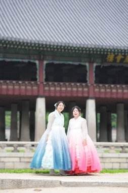 Haziran 'da Seul' de, yirmili yaşlardaki iki Koreli kadın Gyeongbokgung Sarayı 'ndaki tarihi bir salonda poz veriyor, parlak bir yaz gökyüzünün altında pembe ve gökyüzü mavisi bir Hanbok giyiyorlar. Seul, Haziran.