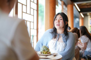 Pencere kenarındaki şık bir kafede, yirmili yaşlardaki sıradan elbiseli iki Koreli kadın içki ve şekerlerle oturur, yumuşak bahar ışığı altında gülüp sohbet ederler. Seul, Jongno Bölgesi, bahar..