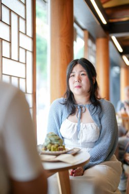 Pencere kenarındaki şık bir kafede, yirmili yaşlardaki sıradan elbiseli iki Koreli kadın içki ve şekerlerle oturur, yumuşak bahar ışığı altında gülüp sohbet ederler. Seul, Jongno Bölgesi, bahar..