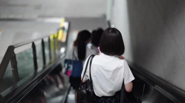 Yazlık üniformalı Japon liseli kızlar asansörle metroya iniyorlar.