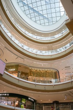 Bir alışveriş merkezinin içinde, merdivenler yüksek tavanların altında mırıldanırken, müşteriler dükkan vitrinlerinin önünden geçerken, modern bir sahne yansımaları oluşuyor. Hongkou Bölgesi, Şangay, Çin. 2 Haziran 2025. Bahar.