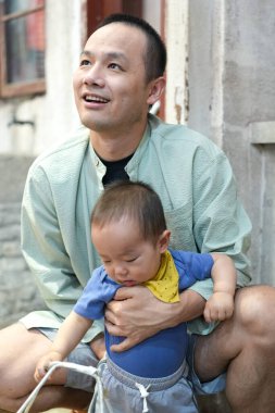 Eski bir alışveriş merkezinde, Çinli bir aile mutfak setinde toplanıyor; bir yaşındaki bir çocuk bebek arabasında, on yaşın altındaki çocuklar ise otuzlu yaşlardaki yetişkinler yemek pişirip sohbet ederken. Şangay, Çin. Bahar.