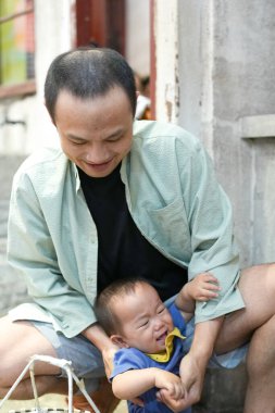 Eski bir alışveriş merkezinde, Çinli bir aile mutfak setinde toplanıyor; bir yaşındaki bir çocuk bebek arabasında, on yaşın altındaki çocuklar ise otuzlu yaşlardaki yetişkinler yemek pişirip sohbet ederken. Şangay, Çin. Bahar.