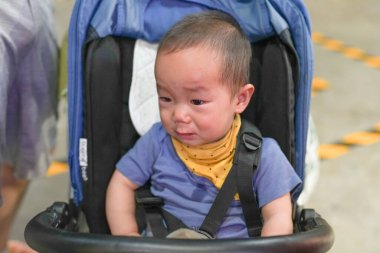 Eski bir alışveriş merkezinde, Çinli bir aile bebek arabasıyla gezer, nostaljik mağazalar ve fenerlerle gezer, aileler gülümserken. Şangay, Çin. Bahar.