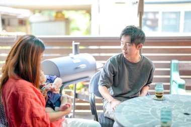 A man and a woman are sitting at a table with a baby in front of them. The man is talking to the woman, and they seem to be enjoying their time together