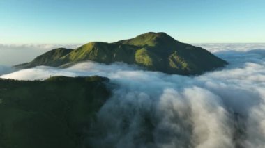 Gün doğumunda bulutların üstündeki dağların havadan görünüşü. Mongkrang Hills, Endonezya 'da