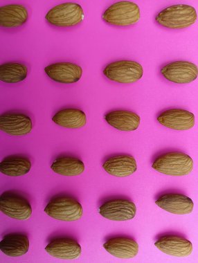 Pembe arka planda sağlıklı taze bademler 